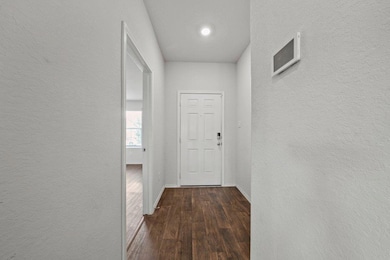 Hall featuring a textured wall, baseboards, and d