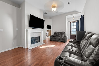 Living area with wood finished floors, a tiled fireplace, and a ceiling fan