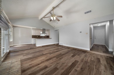 Unfurnished living room featuring dark wood-style floors, ceiling fan, and a textured ceiling