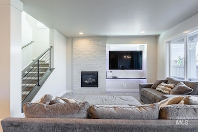 Living area featuring a large fireplace, stairway, and recessed lighting