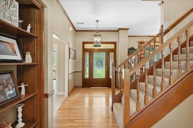 Entrance foyer featuring light wood finished floors, ornamental molding, stairs, and baseboards