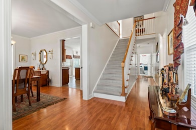 Entryway featuring stairway, wood finished floors, baseboards, and crown molding