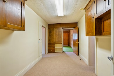 Hall with light colored carpet and baseboards