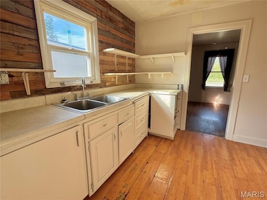 Kitchen with light wood-type flooring, light countertops, open shelves, and wood walls