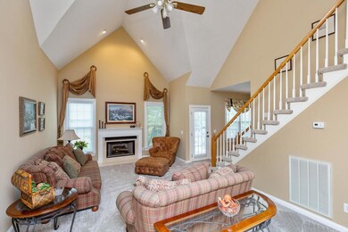 Living Room has soaring ceilings, fireplace with gas logs, door to deck, new carpet and custom drapes