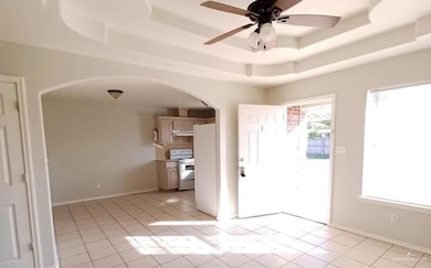 Entryway with arched walkways, a tray ceiling, ceiling fan, and light tile patterned flooring