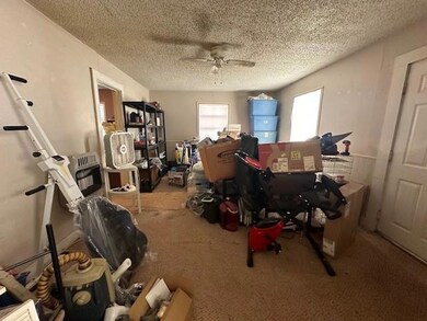 Office area with a textured ceiling, carpet flooring, and ceiling fan