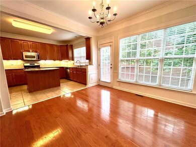 Stairway with a chandelier, healthy amount of natural light, crown molding, wood finished floors, and wainscoting