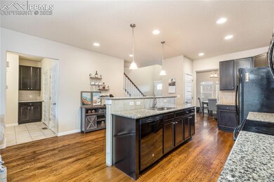 Kitchen featuring breakfast bar, dark brown cabinetry, black appliances, and light granite countertops.
