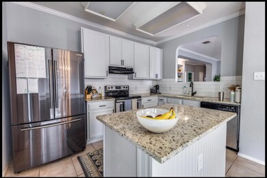 Kitchen featuring appliances with stainless steel finishes, white cabinetry, ornamental molding, decorative backsplash, and light stone counters