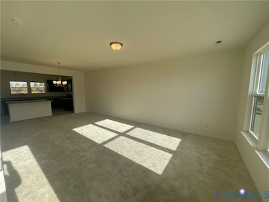 Unfurnished living room featuring light colored carpet and a chandelier