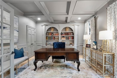 Off the foyer, a private office features built-in shelving, marble flooring, and coffered ceilings.