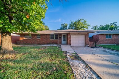 Single story home with a garage and a front lawn