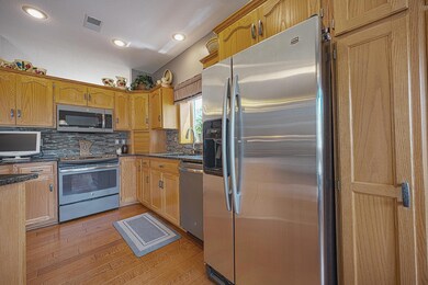 Open design living room/kitchen/dining room area has 9 ft ceilings, granite counter tops, stainless steel appliances, real hardwood flooring, and a gorgeous gas fireplace.