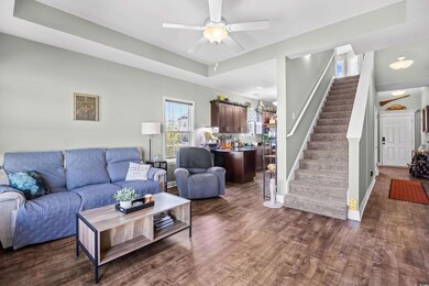 Living area featuring dark wood-style floors, stairway, and ceiling fan
