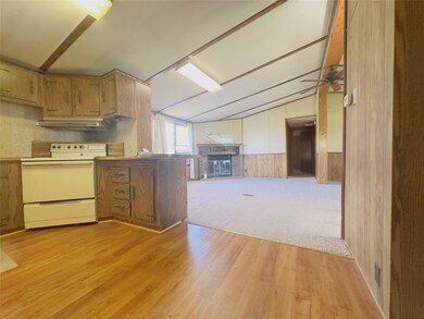 Kitchen with a fireplace, ceiling fan, vaulted cei