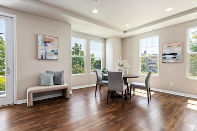 Dining space with laminate wood-style flooring, recessed lighting, and a raised ceiling lots of natural light