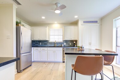 Kitchen with dark countertops, a breakfast bar, a sink, light wood-style floors, and freestanding refrigerator