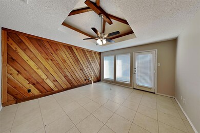 Tiled empty room with a textured ceiling, wood wal