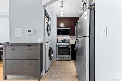 Kitchen with stainless steel appliances, stacked washer / dryer, tasteful backsplash, light countertops, and dark brown cabinets