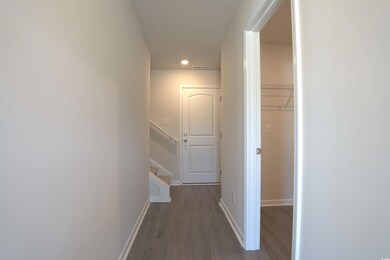 Hallway with wood finished floors, recessed lighting, and stairs