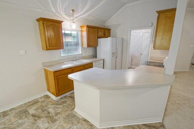 Kitchen and laundry room just past refrigerator.