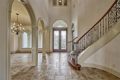 This is a great view of the double front door with a amazing transom window showing the access to the formal dinning room with an amazing chandelier and the main spiral staircase.