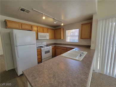 Kitchen featuring white appliances, a sink, rail l