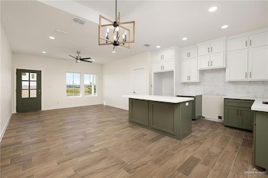 Kitchen with green cabinets, white cabinets, a chandelier, decorative backsplash, and recessed lighting