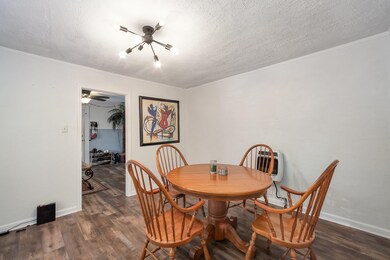Dining space with a chandelier, dark wood-type flooring, a textured ceiling, and crown molding