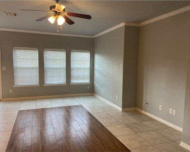 Spare room featuring crown molding, light tile patterned floors, and a ceiling fan