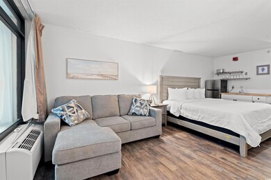 Bedroom featuring freestanding refrigerator, wood finished floors, and bar area