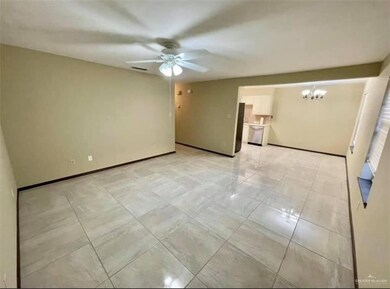 Tiled spare room featuring ceiling fan with notable chandelier