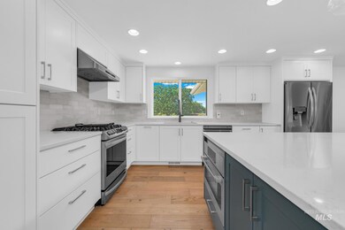Kitchen with stainless steel appliances, exhaust hood, white cabinetry, recessed lighting, and backsplash