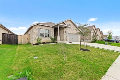 View of front facade featuring driveway, brick siding, a garage, and covered porch