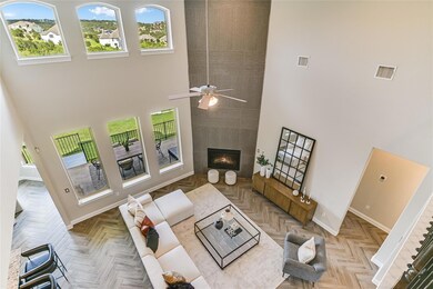 Living room with plenty of natural light, a high ceiling, a tiled fireplace, and ceiling fan