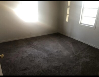 Unfurnished room with dark carpet and baseboards