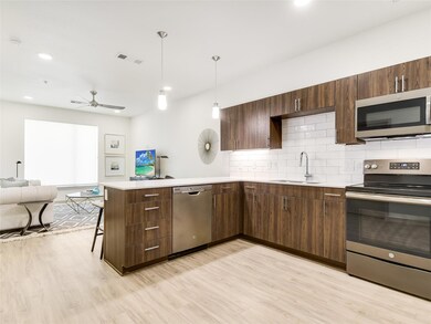 Kitchen featuring a sink, open floor plan, light wood finished floors, a peninsula, and appliances with stainless steel finishes