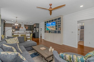 Living room featuring ceiling fan, dark wood-style floors, a chandelier, recessed lighting, and a textured ceiling