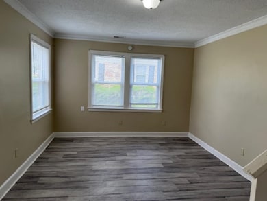 Den lenty of natural light, dark LVP floors, crown molding, and baseboards