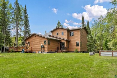 Rear view of house featuring a wooden deck and a lawn