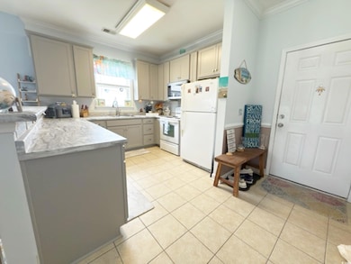 Kitchen featuring crown molding, visible vents, a peninsula, white appliances, and light countertops