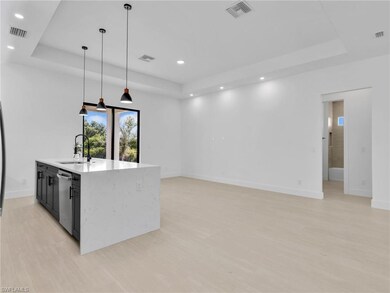 Kitchen featuring a tray ceiling, hanging light fixtures, light stone countertops, light wood finished floors, and recessed lighting
