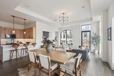 Dining space with a raised ceiling, a notable chandelier, dark wood finished floors, and baseboards