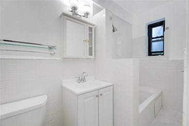 Bathroom featuring tile walls, vanity, a tub, and a shower