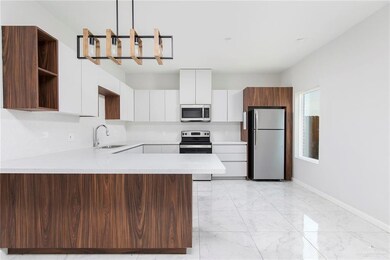 Kitchen featuring appliances with stainless steel finishes, open shelves, a sink, light marble finish floors, and light countertops