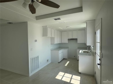 Kitchen featuring white cabinetry, light countertops, a raised ceiling, and light tile patterned floors
