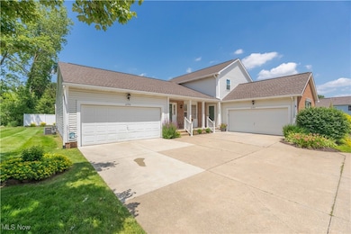 Traditional-style house with an attached garage, driveway, a front yard, covered porch, and roof with shingles