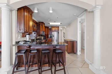 Kitchen featuring arched walkways, ornate columns, light tile patterned floors, and a kitchen bar