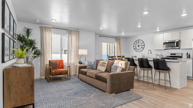 Living area featuring a textured ceiling, light wood finished floors, and recessed lighting